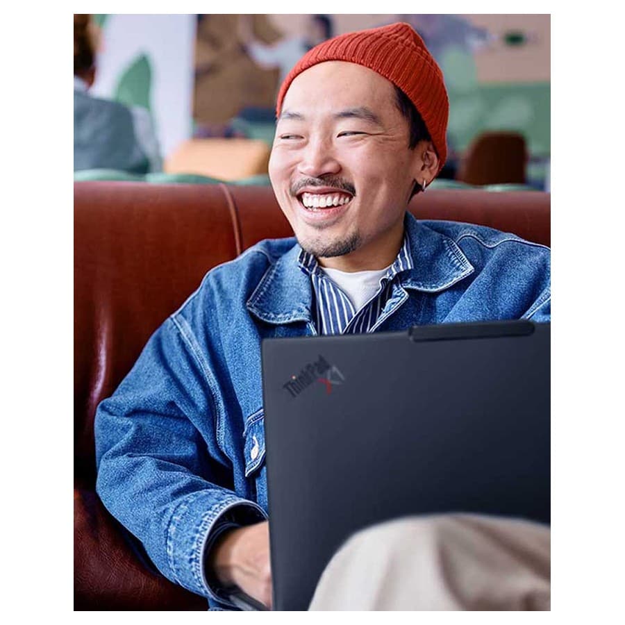A man smiling while using his ThinkPad at a coffee shop. Lenovo sale