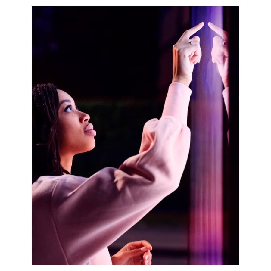 A woman looking at purple and red lights projected on a wall. Lenovo sale
