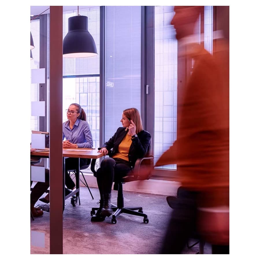 Work colleagues in a glass walled room with a passerby in front. Lenovo sale