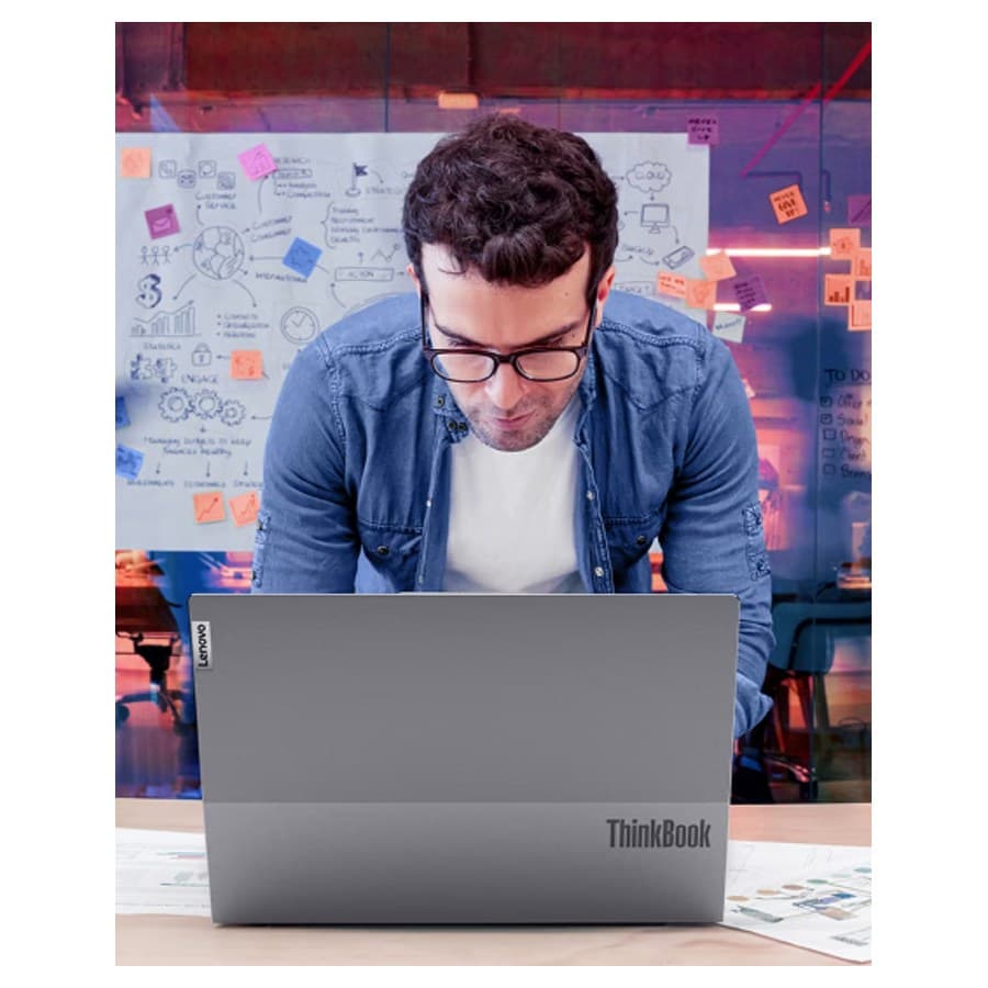 Man working at his Lenovo laptop with post it note board in the background. Lenovo sale